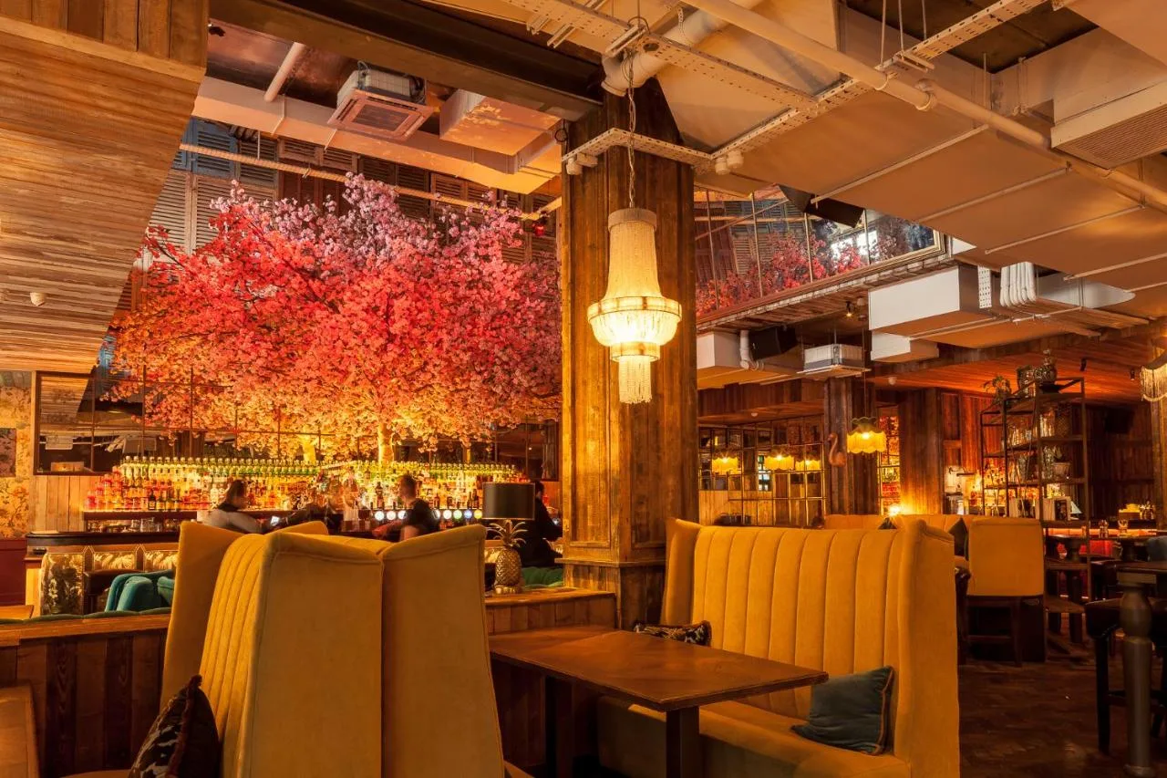 a restaurant with a bar with yellow chairs at House Belfast Hotel in Belfast