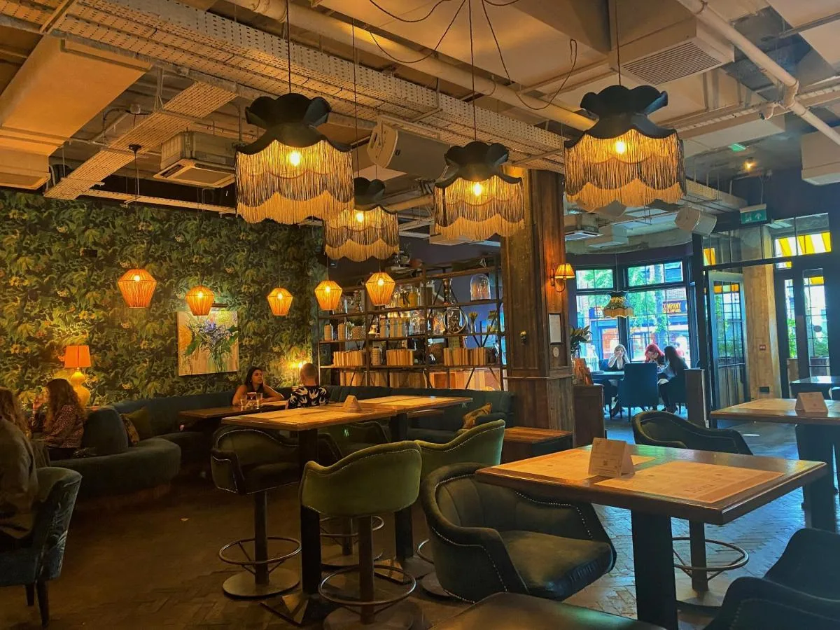 a restaurant with tables and chairs and chandeliers at House Belfast Hotel in Belfast
